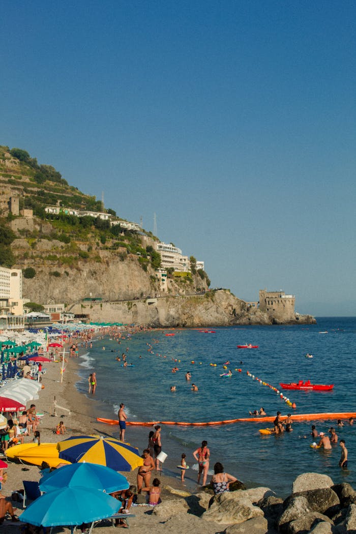 Capture the essence of summer at Maiori beach on Italy's Amalfi Coast, with vibrant umbrellas and scenic cliffs.