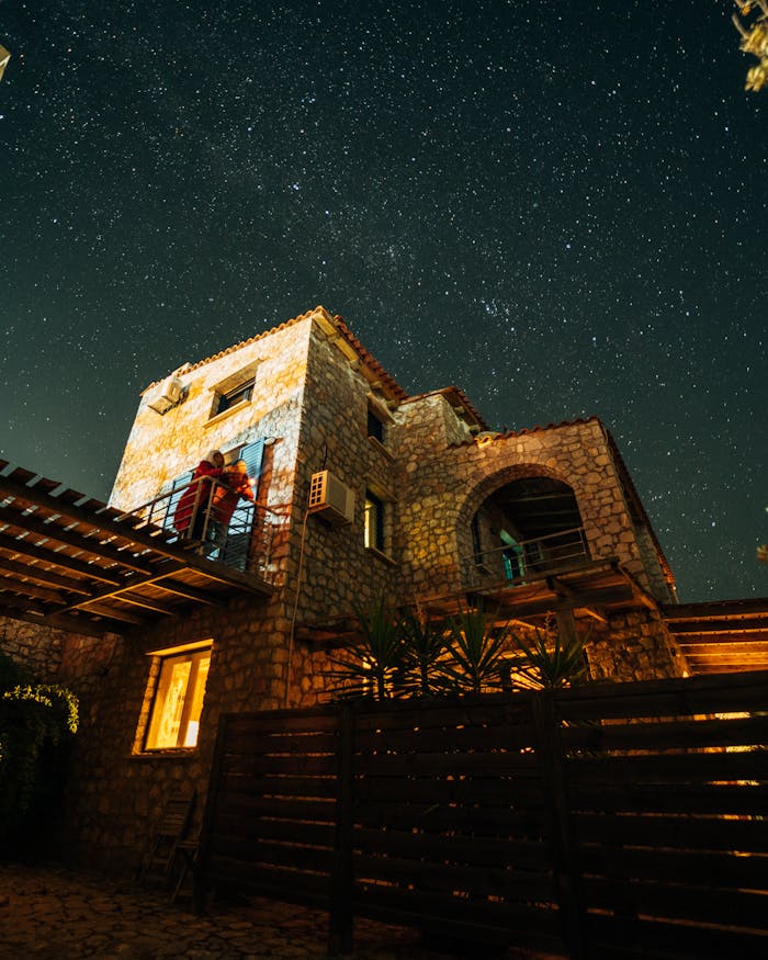 A picturesque stone house in Greece with a mesmerizing starry night sky. Perfect for travel and architecture themes.